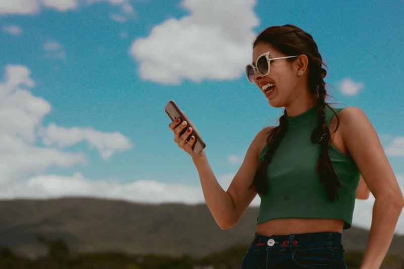 Imagen decorativa: mujer riéndose con su celular en la mano